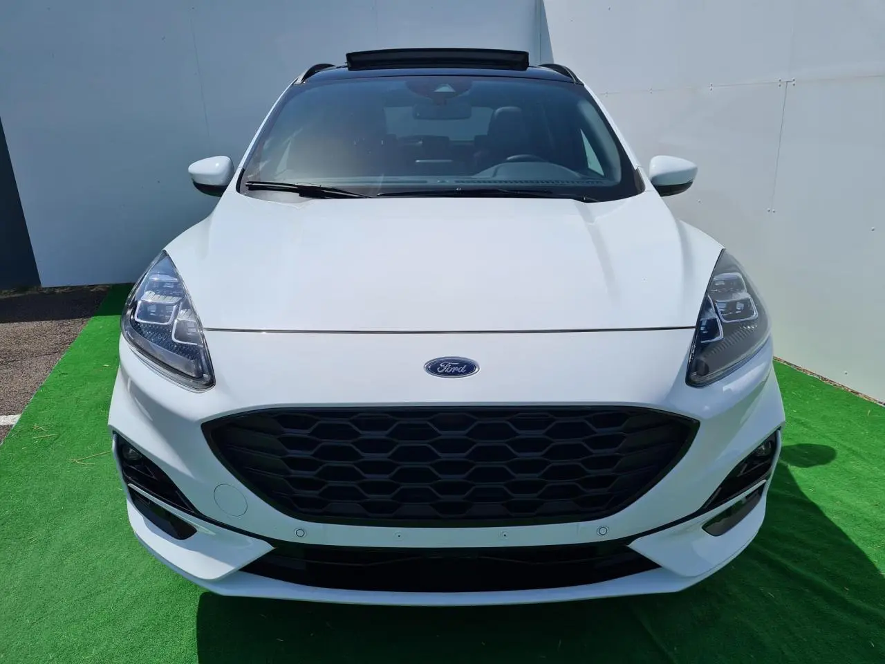 Vue frontale d'un Ford Kuga blanc glacier avec calandre noire hexagonale et phares LED distinctifs.