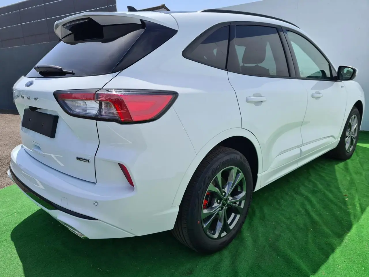 Vue 3/4 arrière droite d'un Ford Kuga blanc glacier hybride rechargeable avec jantes alliage et feux LED distinctifs.