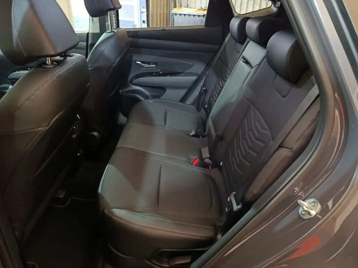 Vue côté droit sur la banquette arrière en cuir noir du Hyundai Tucson 1.6 Hybrid 2025 gris foncé, avec portes ouvertes.