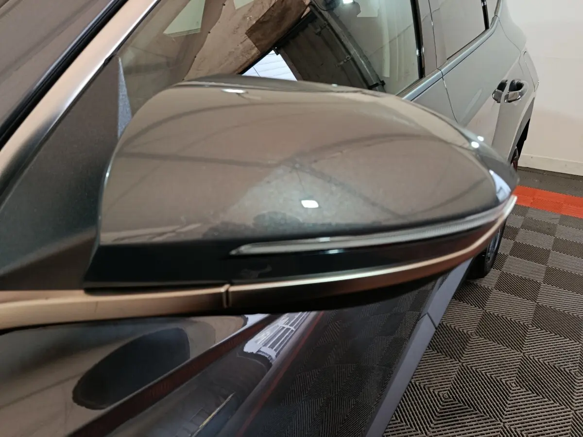 Rétroviseur droit gris foncé du Hyundai Tucson 2025, vue rapprochée avec partie latérale arrière du véhicule visible.