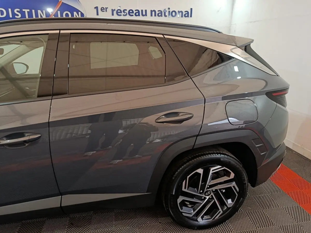 Vue latérale droite du Hyundai Tucson 1.6 Hybrid gris foncé, mettant en valeur la jante alliage et la trappe à carburant.