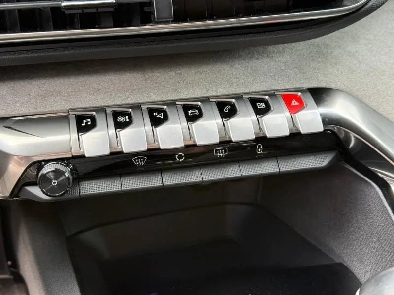 Vue rapprochée des commandes centrales chromées et noires du tableau de bord du Peugeot 3008 gris Platinium 2024.