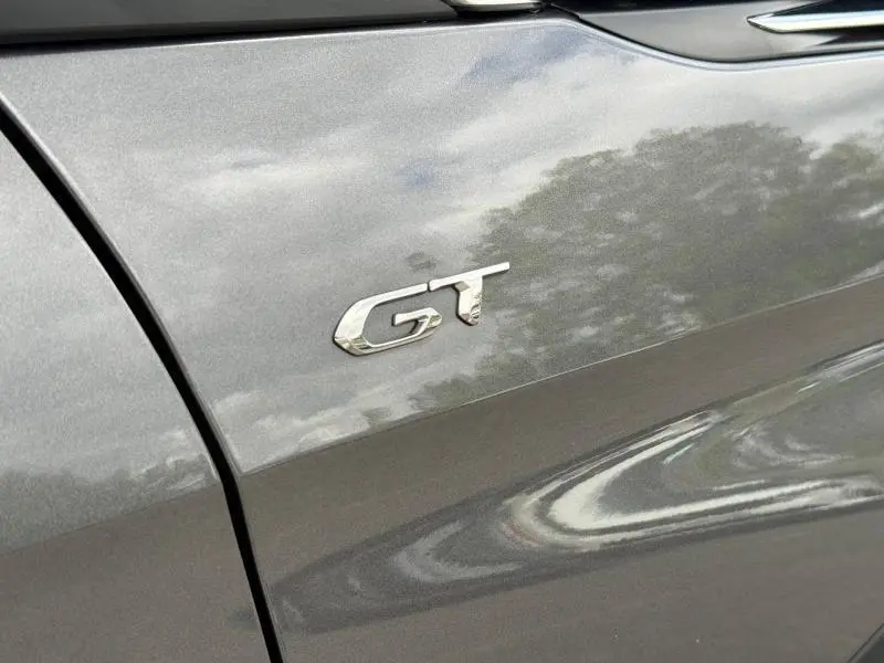 Gros plan sur l’inscription GT sur la portière gris Platinium d’un Peugeot 3008 2024, finition sportive visible.