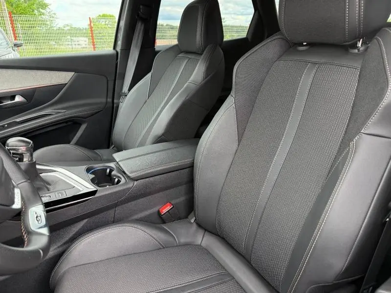 Vue intérieure côté avant droit du Peugeot 3008 1.2 PureTech 130ch GT 2024, sièges Mi-TEP/tissu Belomka noirs avec surpiqûres contrastées.