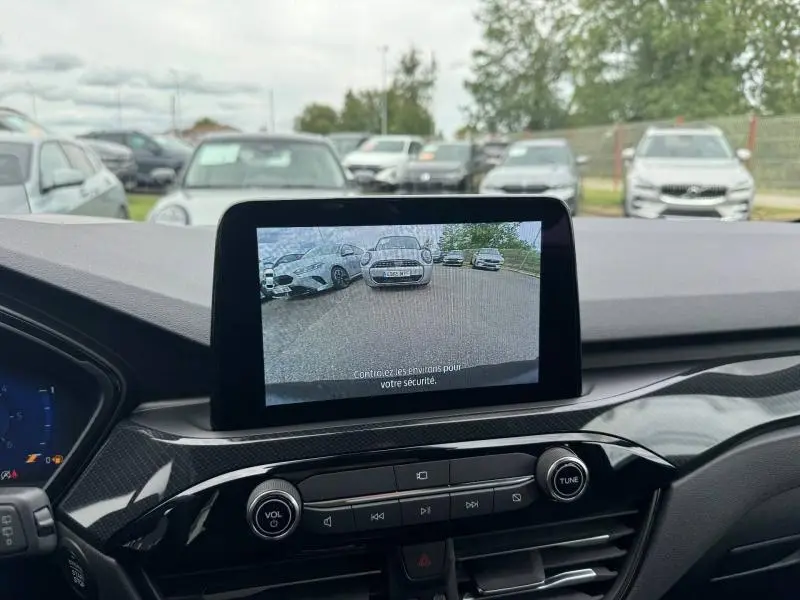 Vue intérieure du tableau de bord du Ford Kuga 2023 avec écran tactile affichant la caméra de recul en marche.