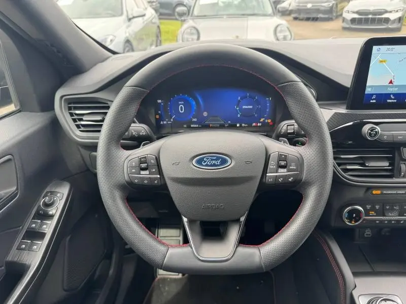 Vue intérieure centrée sur le volant cuir multifonction du Ford Kuga 2023 avec tableau de bord numérique et écran tactile GPS.