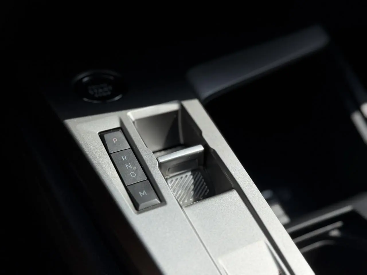 Gros plan sur la console centrale grise métallisée de la Peugeot 308 avec les boutons de la boîte auto et le frein électrique.