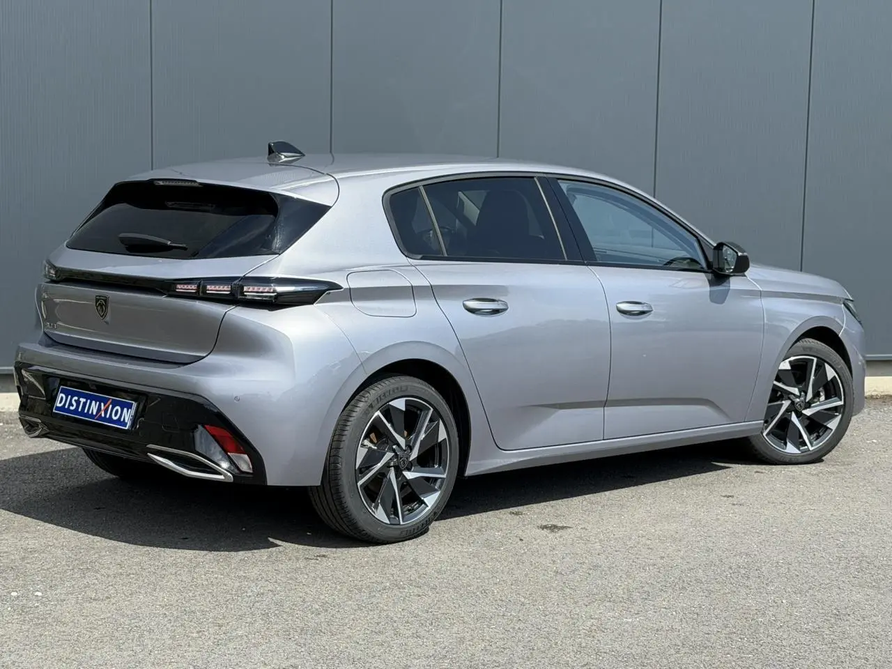 Peugeot 308 gris Artense vue 3/4 arrière droit, jantes alliage 17'' et bandeau noir brillant entre feux arrière.