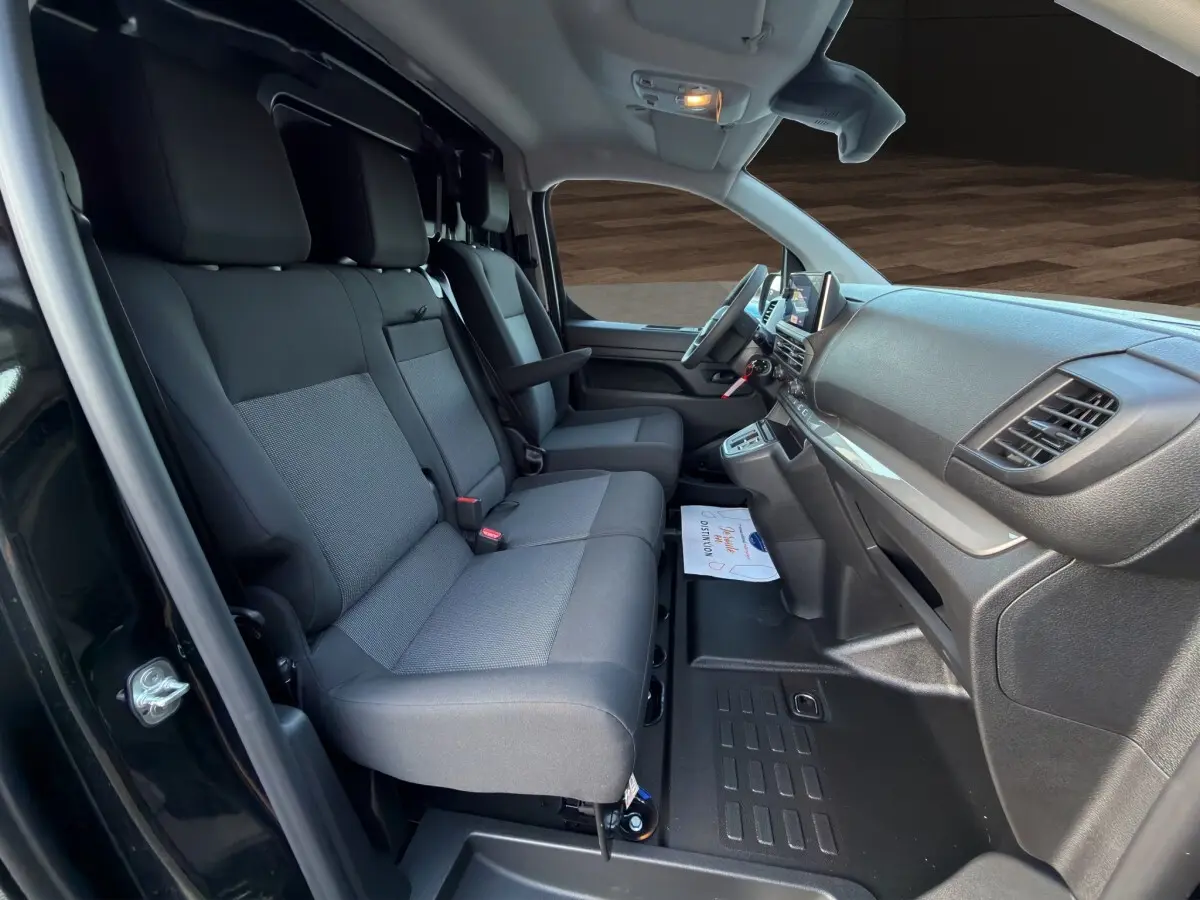 Vue intérieure côté conducteur du Citroën Jumpy noir 2026, montrant les sièges avant et le tableau de bord moderne.