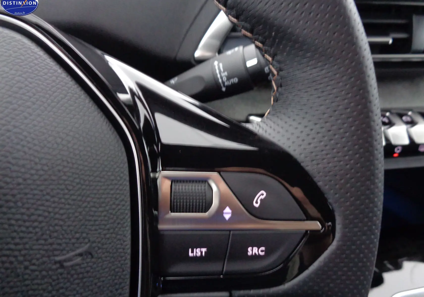 Gros plan sur les commandes gauche du volant en cuir perforé noir du Peugeot 3008 GT 2023, avec boutons lumineux.