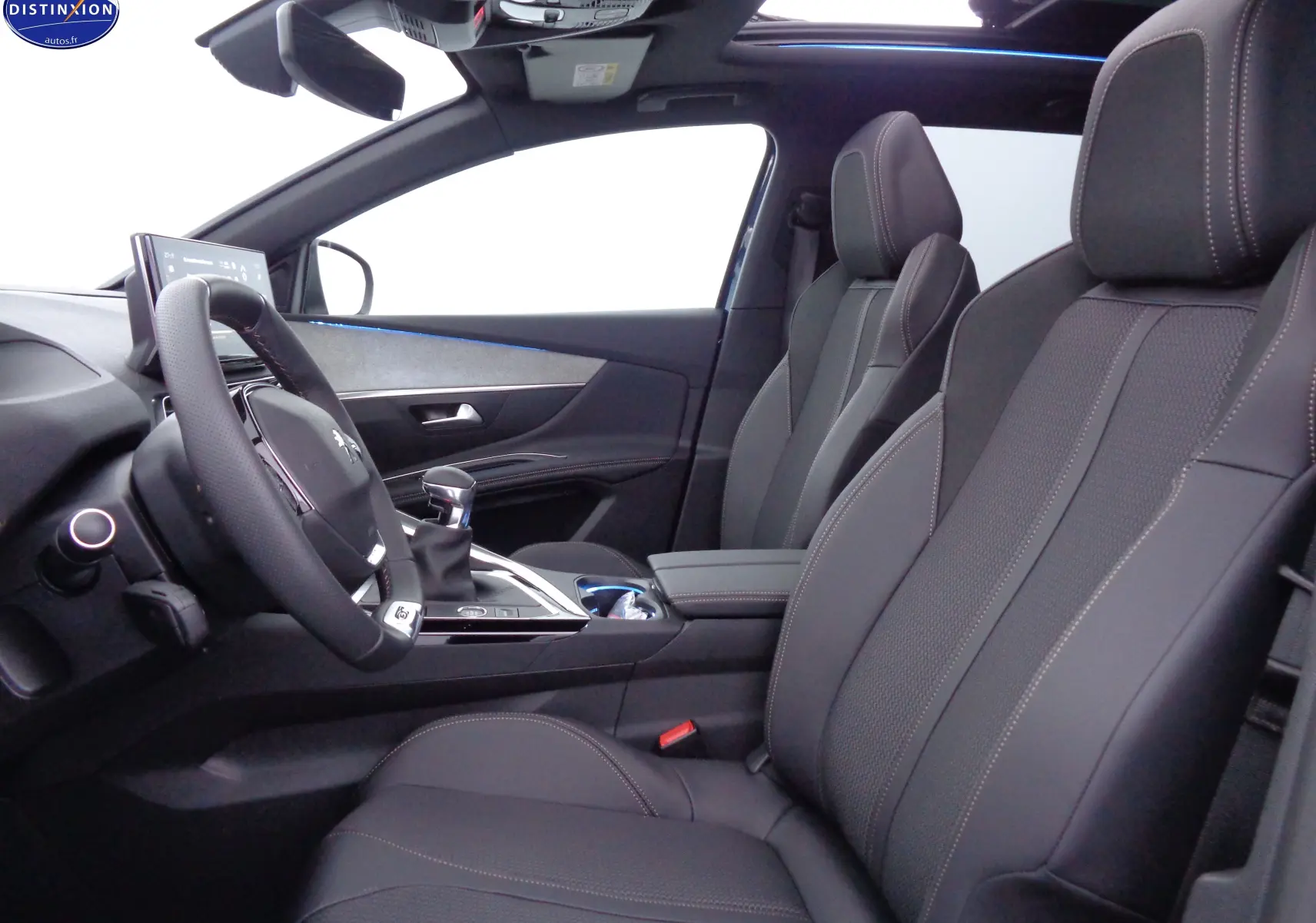 Intérieur du Peugeot 3008 2023 vu côté conducteur, sièges cuir noir avec surpiqûres et toit panoramique ouvert.