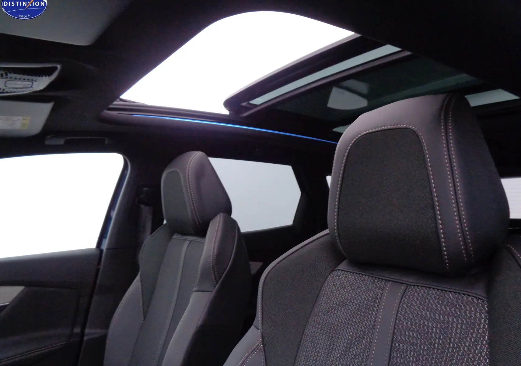 Intérieur du Peugeot 3008 2023 bleu Celebes, vue sur sièges avant en cuir noir et toit ouvrant panoramique.