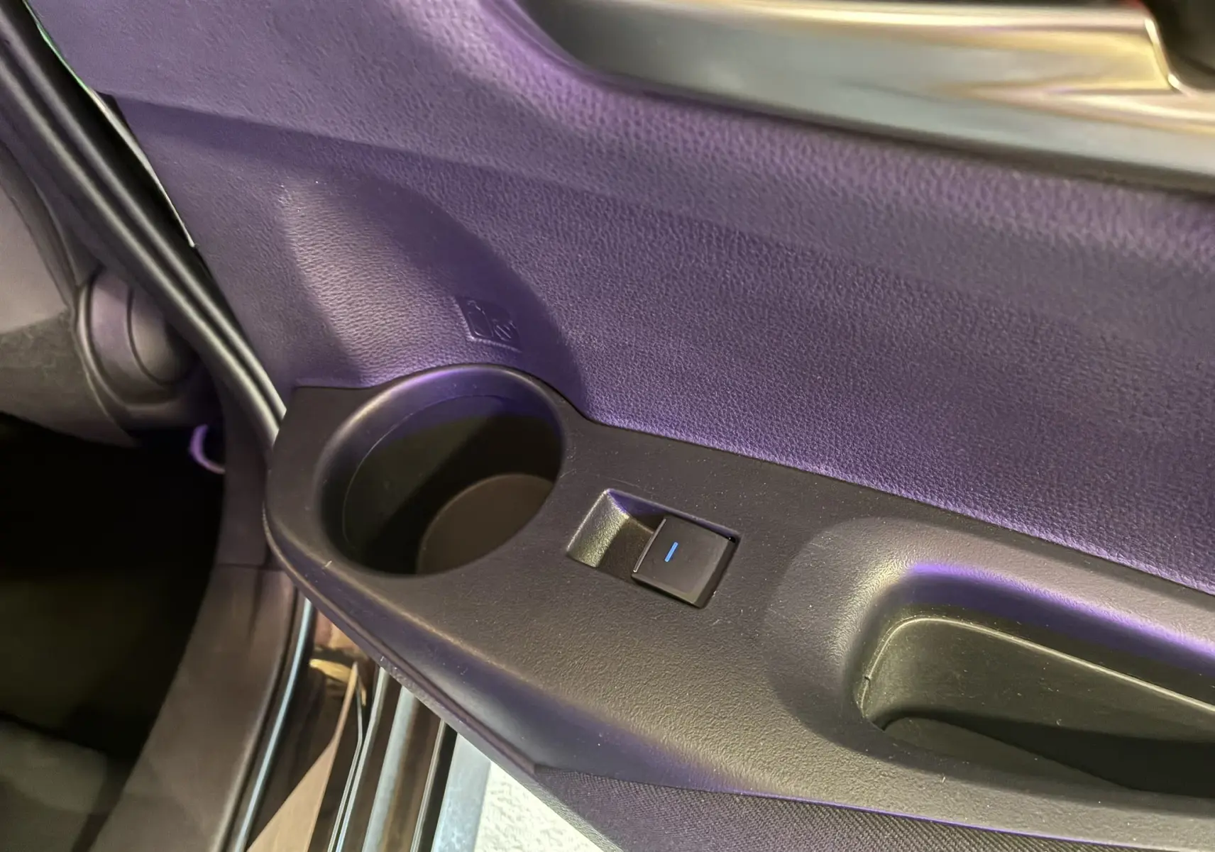 Gros plan sur la poignée intérieure et le bouton de lève-vitre côté gauche de la porte noire d'une Toyota Corolla 2020.