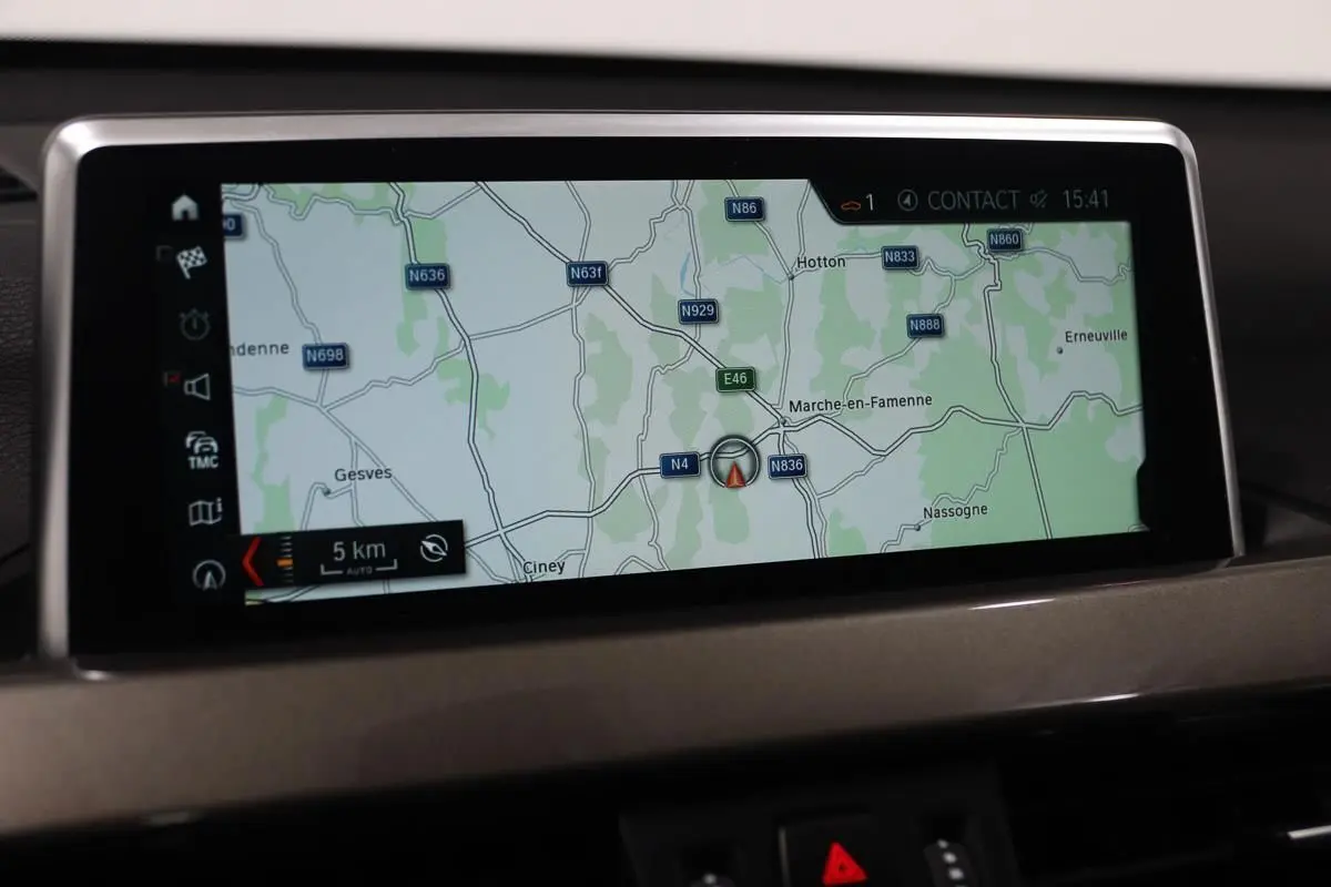 Écran de navigation GPS intégré au tableau de bord d'un BMW X1 sDrive 18D argent, affichant une carte routière.