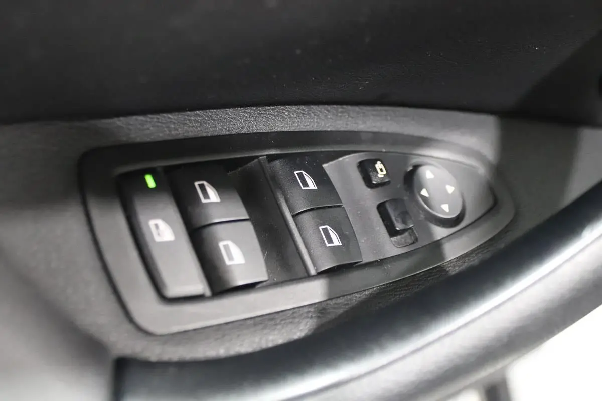 Commande des vitres électriques et réglage des rétroviseurs sur la porte côté conducteur d'une BMW X1 argentée 2019.