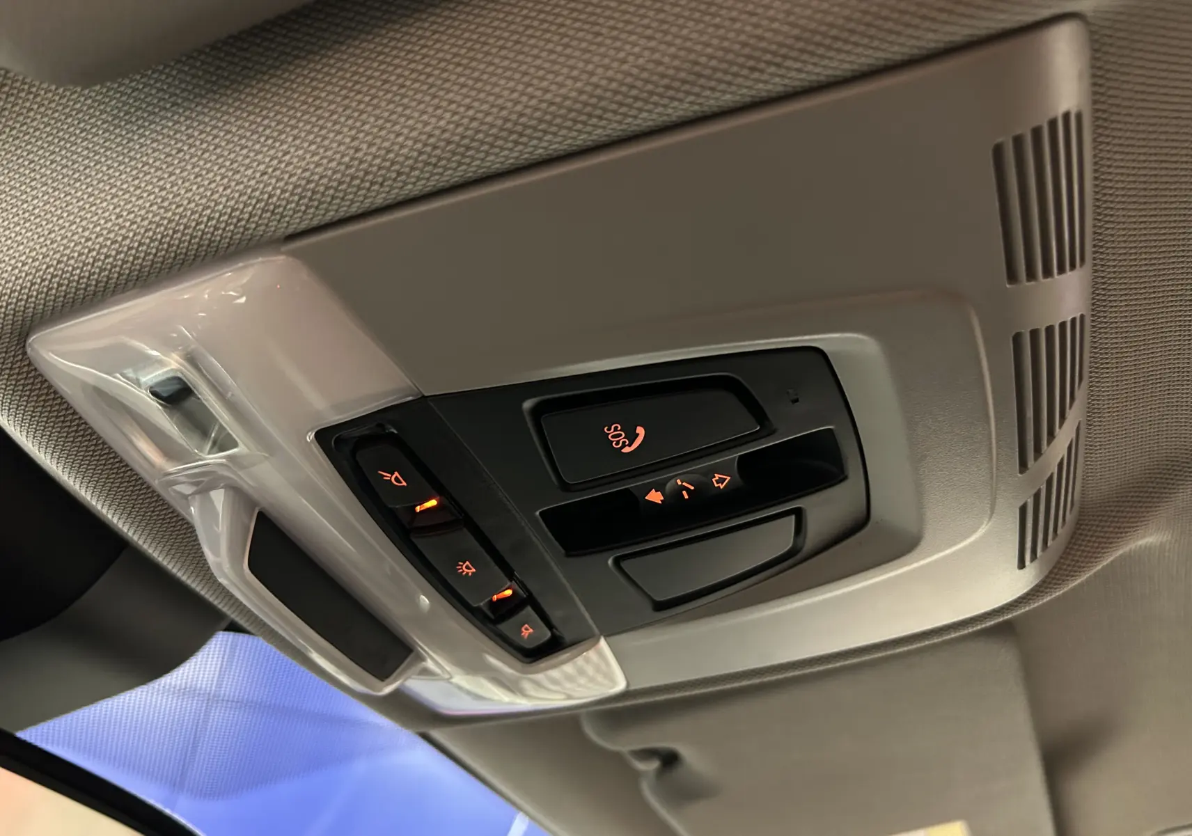 Vue en gros plan du panneau de commandes au plafond avec éclairage orange dans l’habitacle gris clair d’une BMW X1 argent métallisé.
