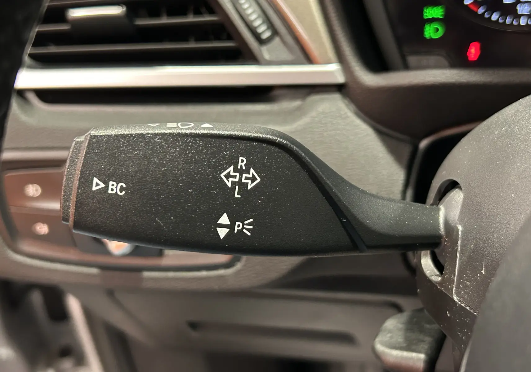 Gros plan sur la manette de clignotant noire à gauche du volant dans l'habitacle d'un BMW X1 argenté de 2019.