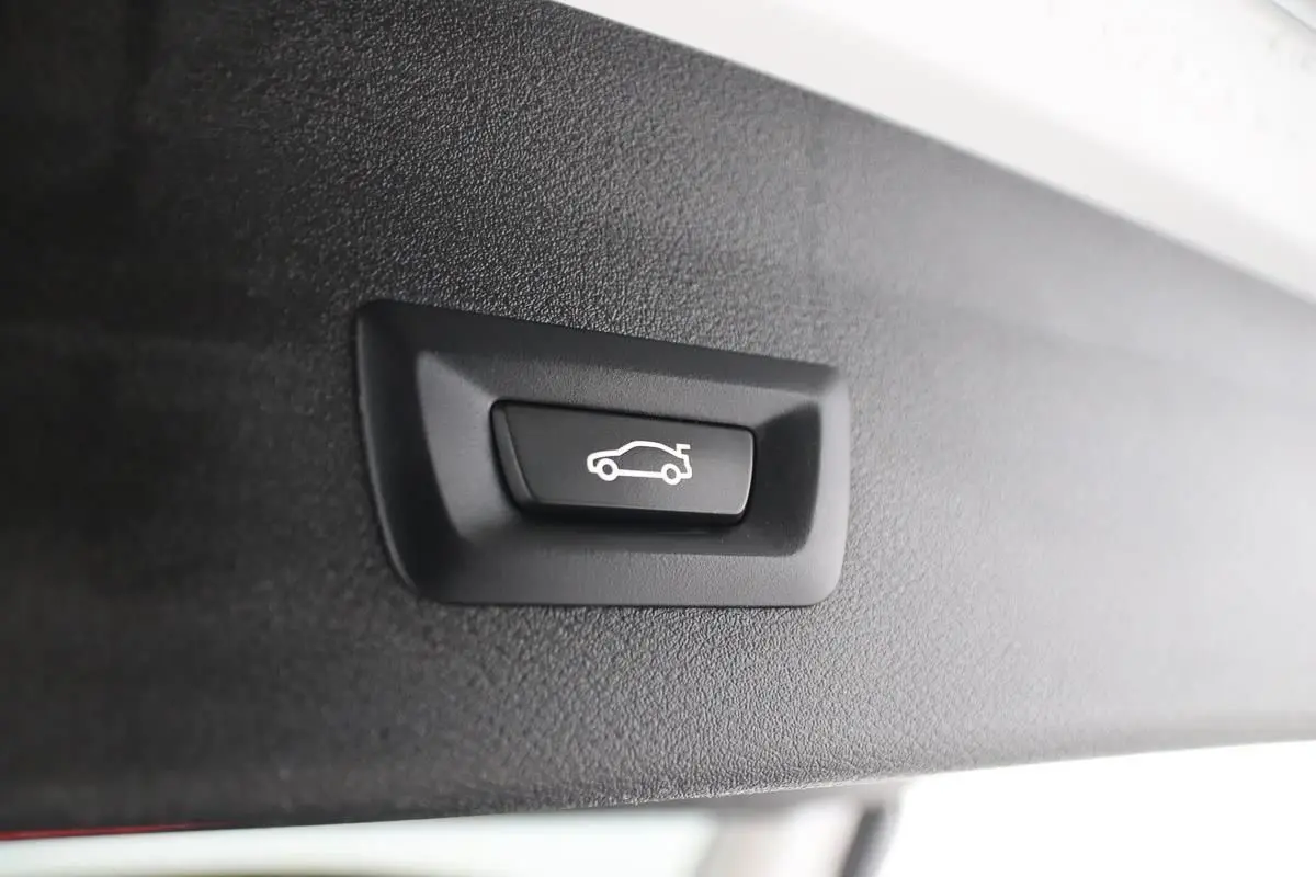 Bouton de fermeture électrique du hayon sur le bord intérieur du coffre d'un BMW X1 argent métallisé.