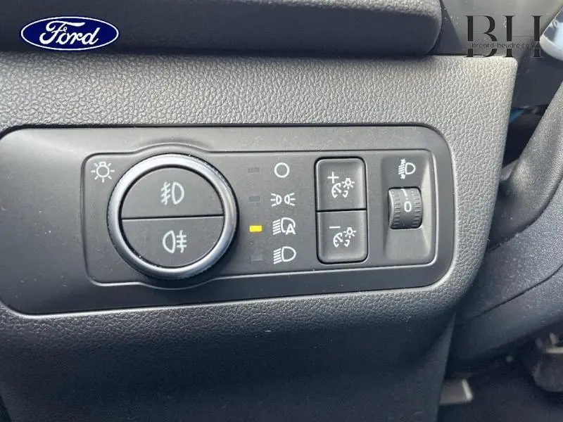Gros plan sur les commandes d’éclairage intérieures du Ford Kuga 2.0 EcoBlue 190ch Titanium bleu azur, tableau de bord noir.