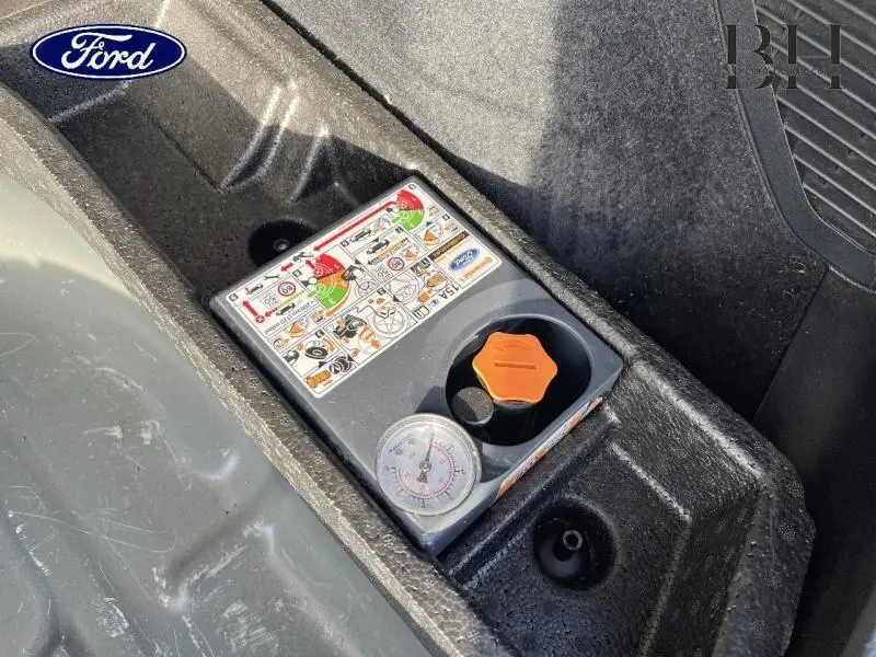 Gros plan sur le compresseur de pneu intégré dans le coffre du Ford Kuga bleu azur métallisé 2020.