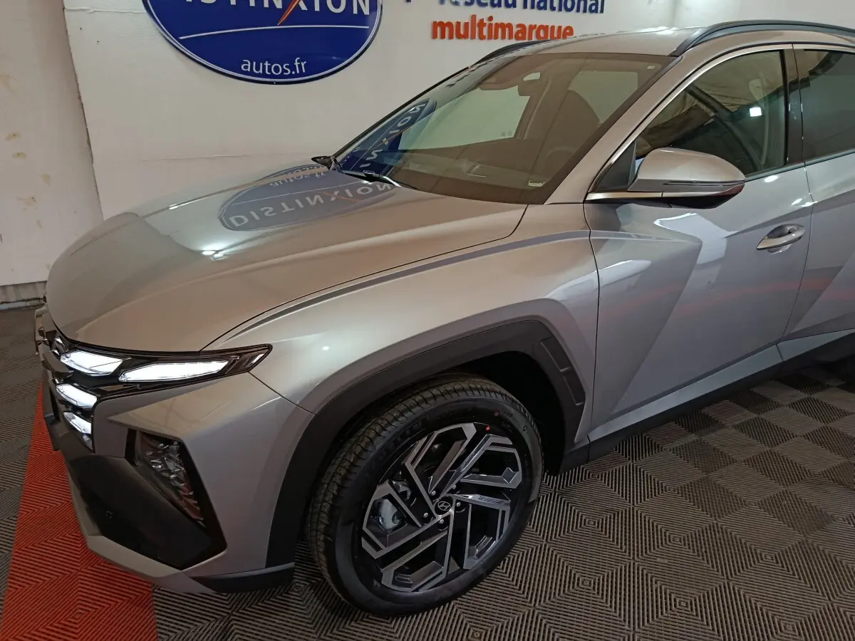 Vue 3/4 avant droit du Hyundai Tucson 2025 gris clair avec phares LED et jantes alliage distinctives.
