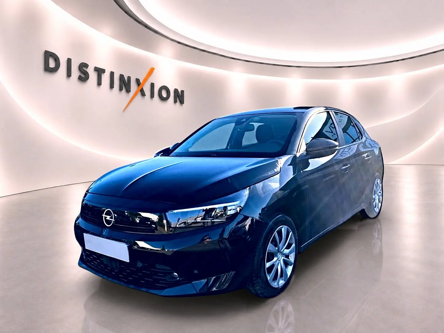 Opel Corsa noire vue 3/4 avant droit dans un showroom lumineux avec logo Distinxion en arrière-plan.