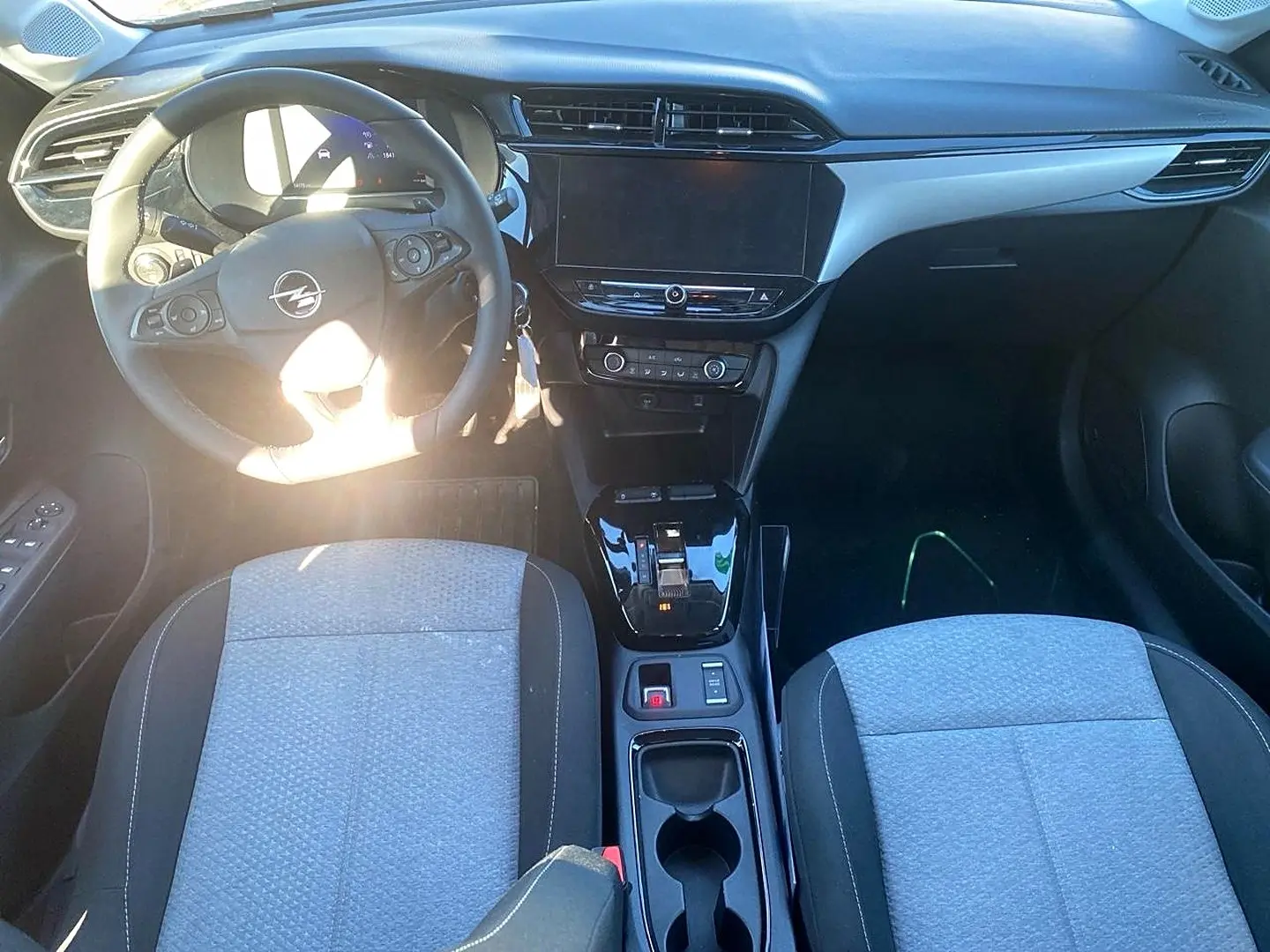 Vue intérieure avant de l'Opel Corsa 2025 avec tableau de bord noir, volant multifonction et sièges tissu gris.