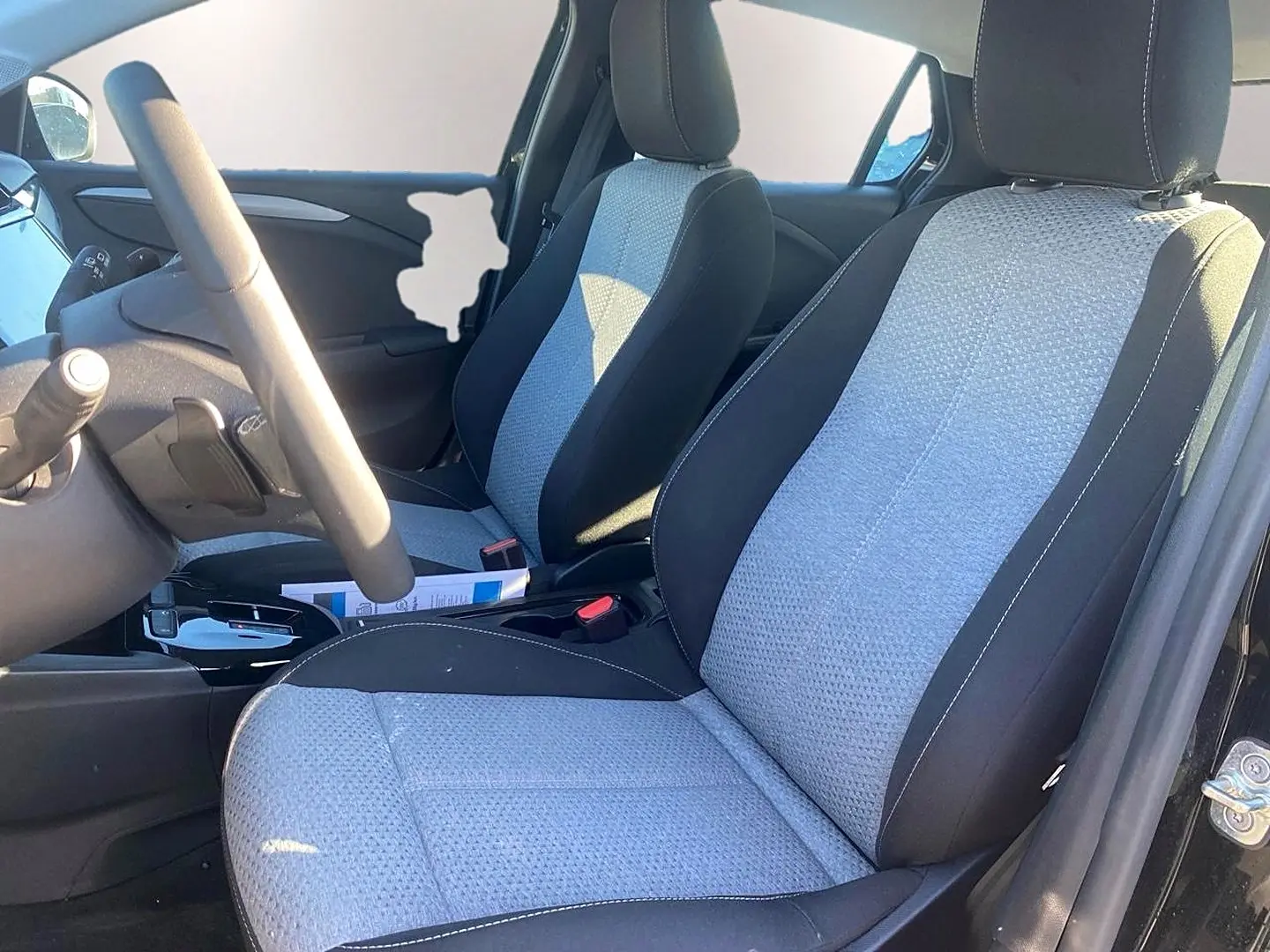 Vue intérieure côté conducteur de l'Opel Corsa 2025, sièges tissu bicolore gris et noir avec volant multifonction.