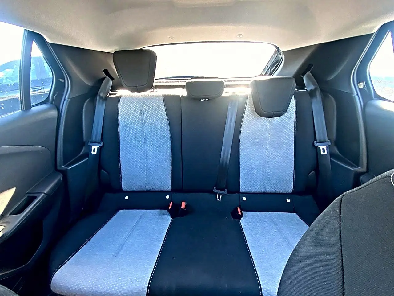 Vue intérieure arrière de la banquette arrière bicolore noire et grise de l’Opel Corsa 2025 avec appuie-têtes et ceintures visibles.