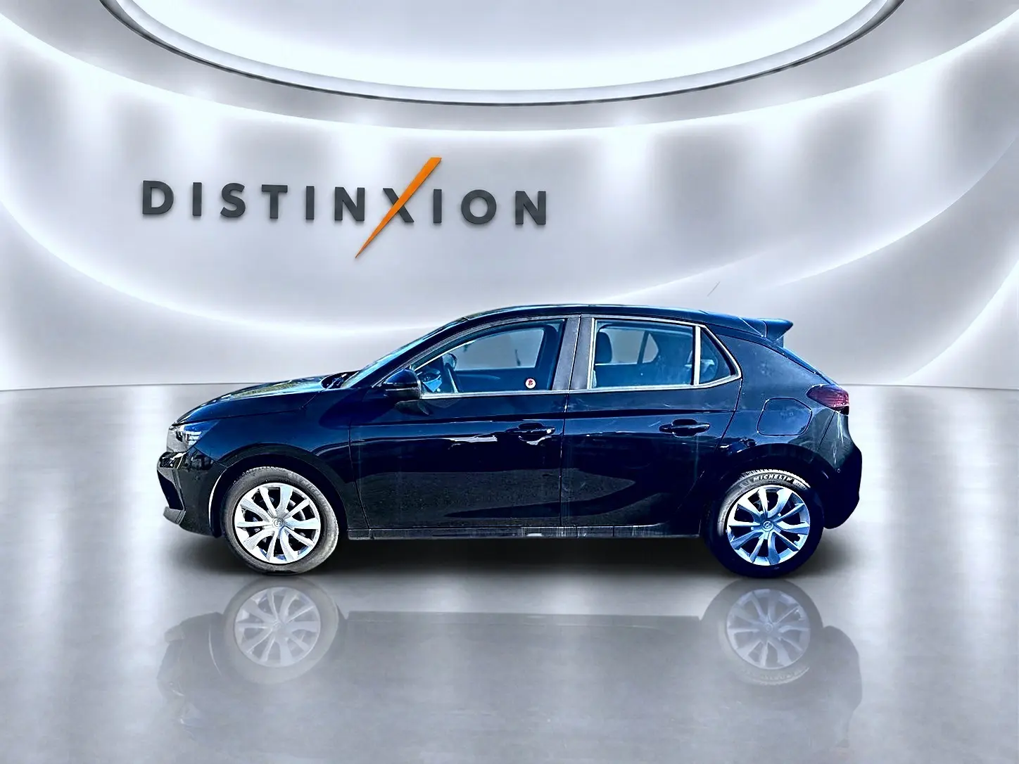 Profil côté gauche d'une Opel Corsa noire 2025 dans un showroom lumineux avec jantes argentées et becquet arrière.
