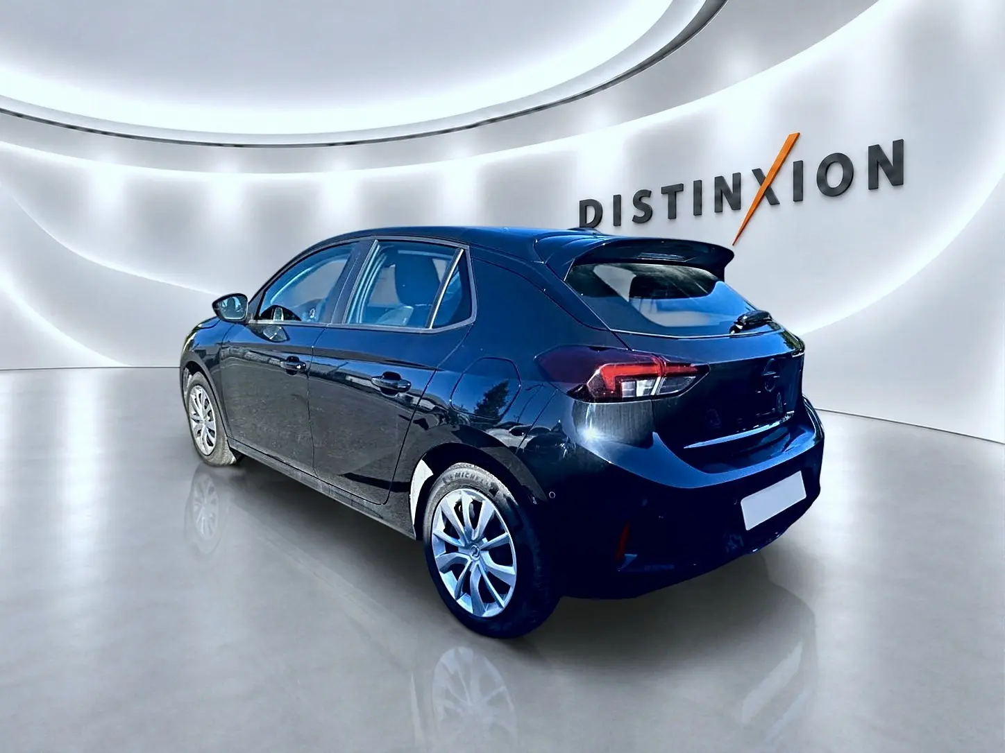 Opel Corsa noire vue 3/4 arrière droit dans un showroom avec becquet et jantes alliage visibles.