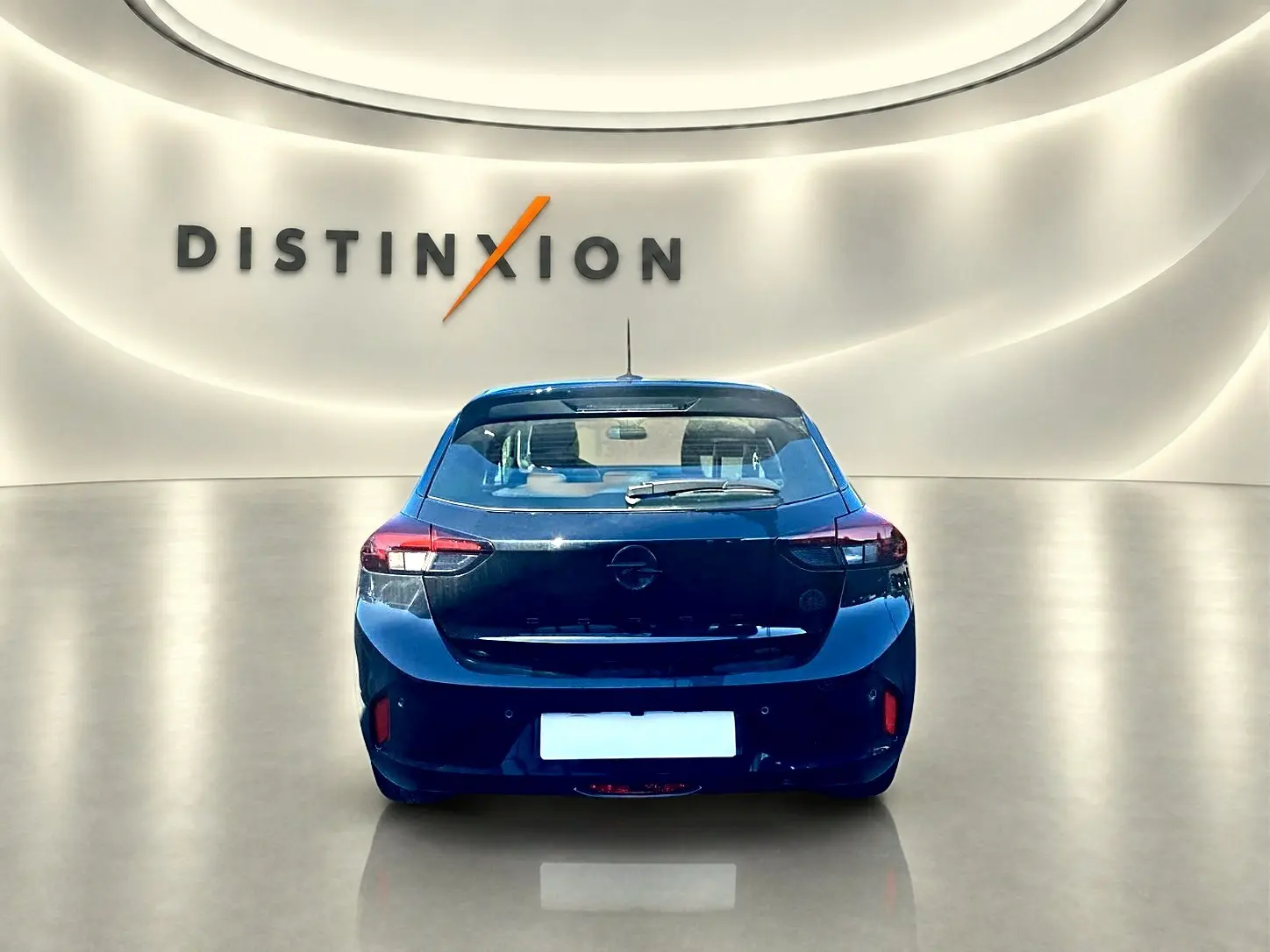 Vue arrière d'une Opel Corsa noire 2025 dans un showroom avec logo Distinxion en arrière-plan.