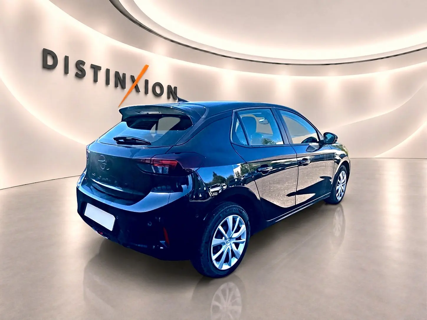 Opel Corsa noire vue 3/4 arrière droit dans un showroom lumineux avec becquet et jantes alliage.
