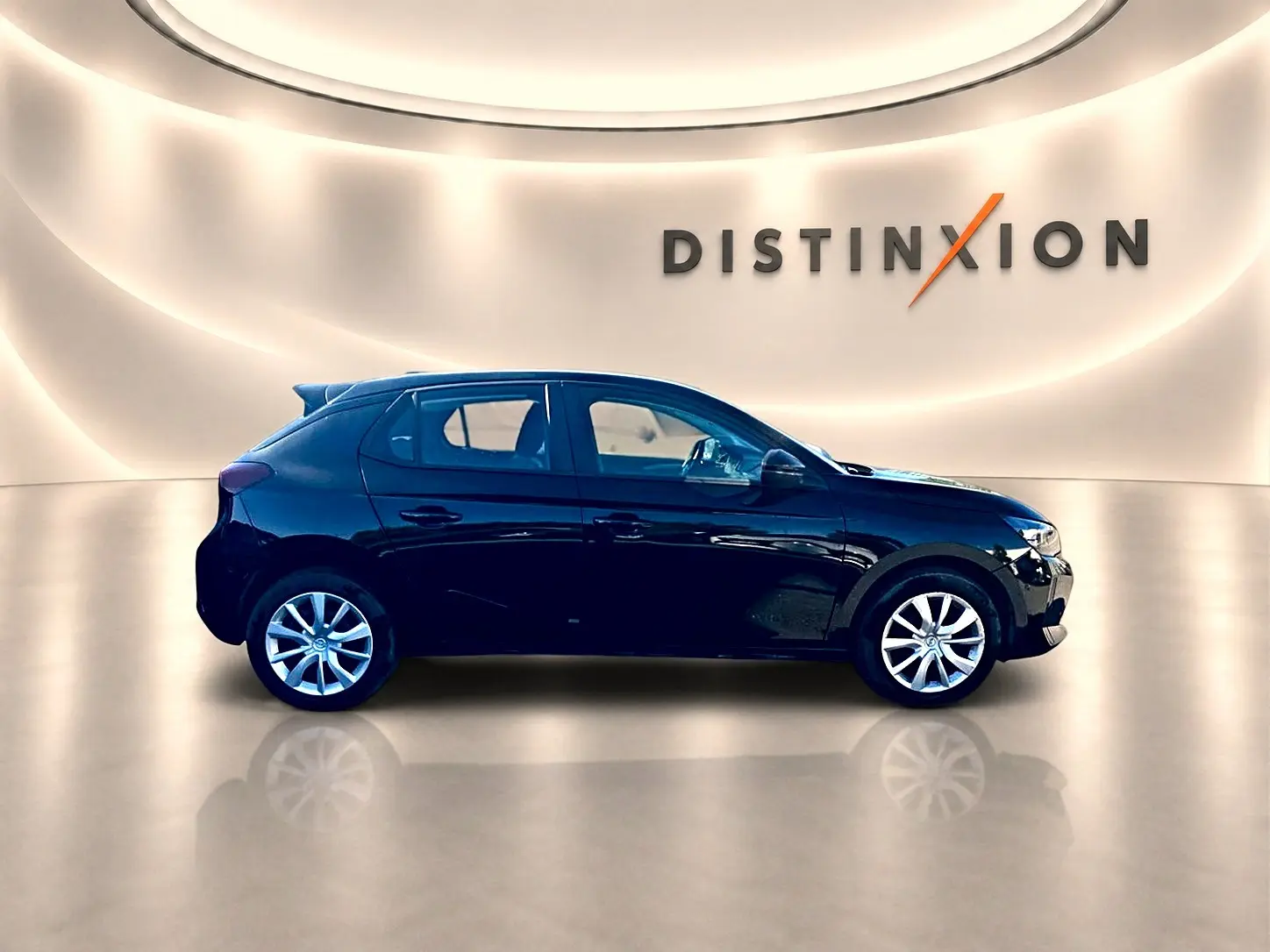 Opel Corsa noire vue de profil côté gauche, avec becquet arrière et jantes argentées dans un showroom lumineux.