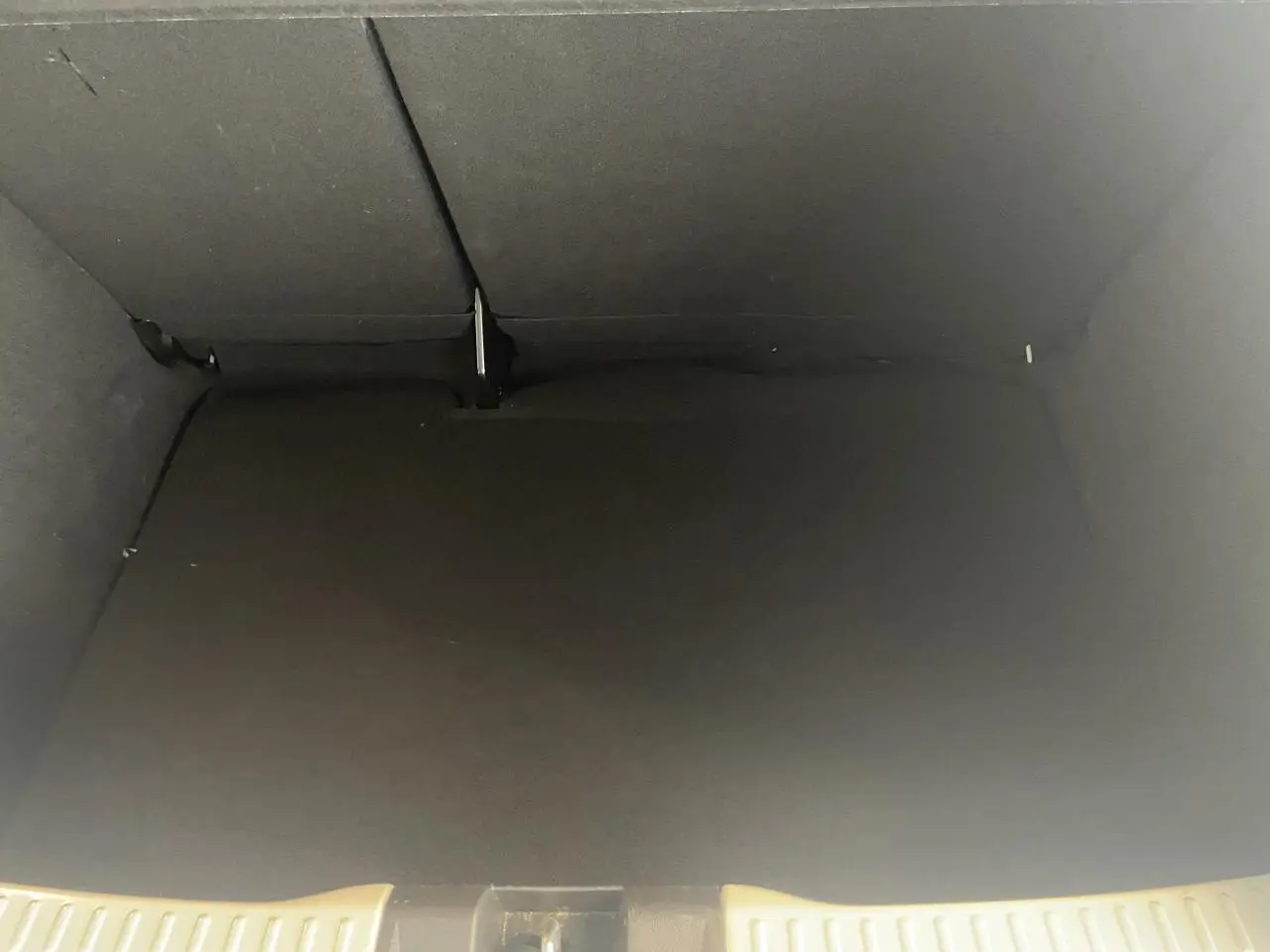 Vue intérieure du coffre noir de la Dacia Sandero 2024, version Expression, avec banquette arrière rabattue.