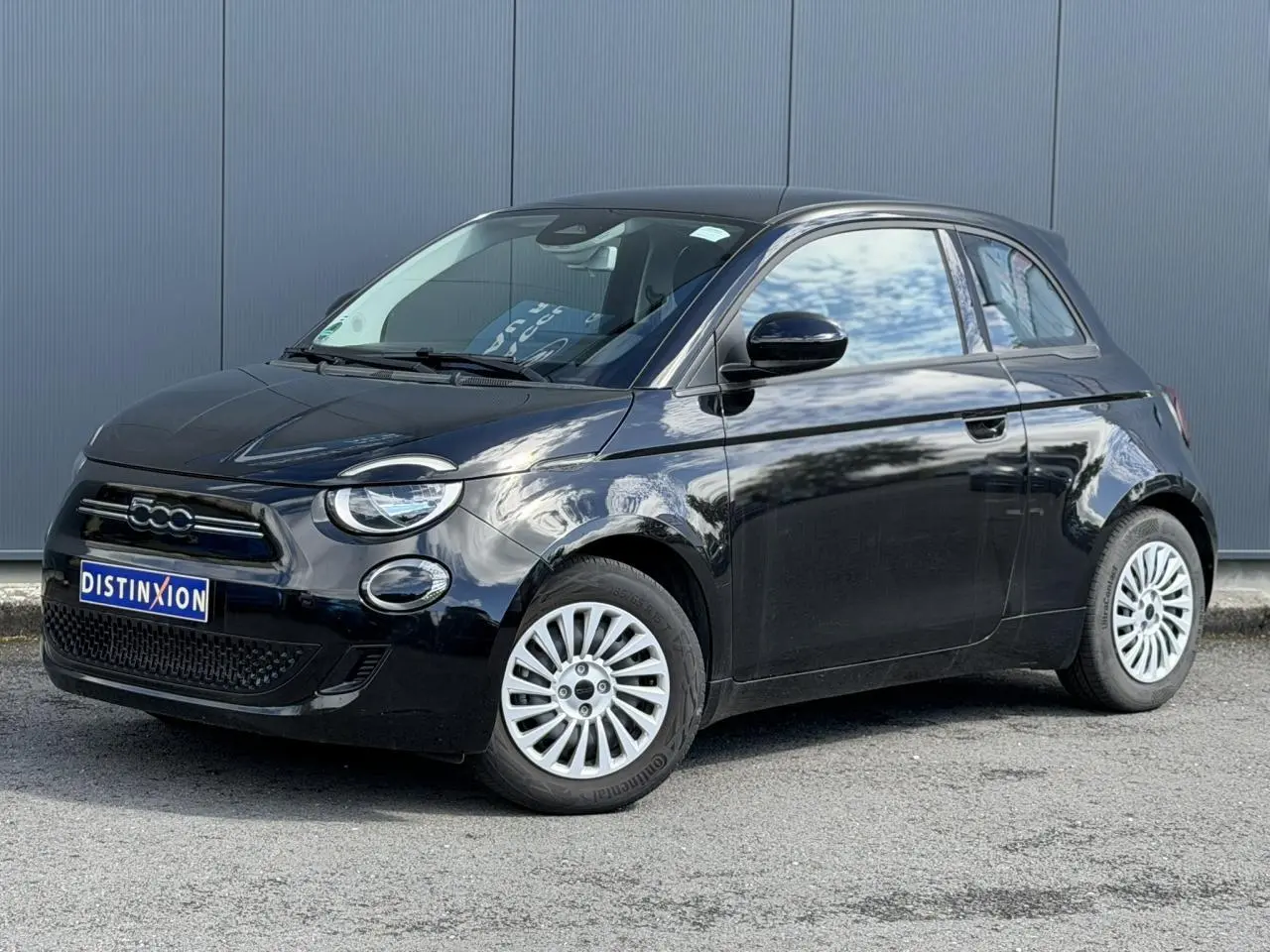 Fiat 500 électrique noire vue en 3/4 avant droit, avec jantes alu 16 pouces et calandre distinctive.
