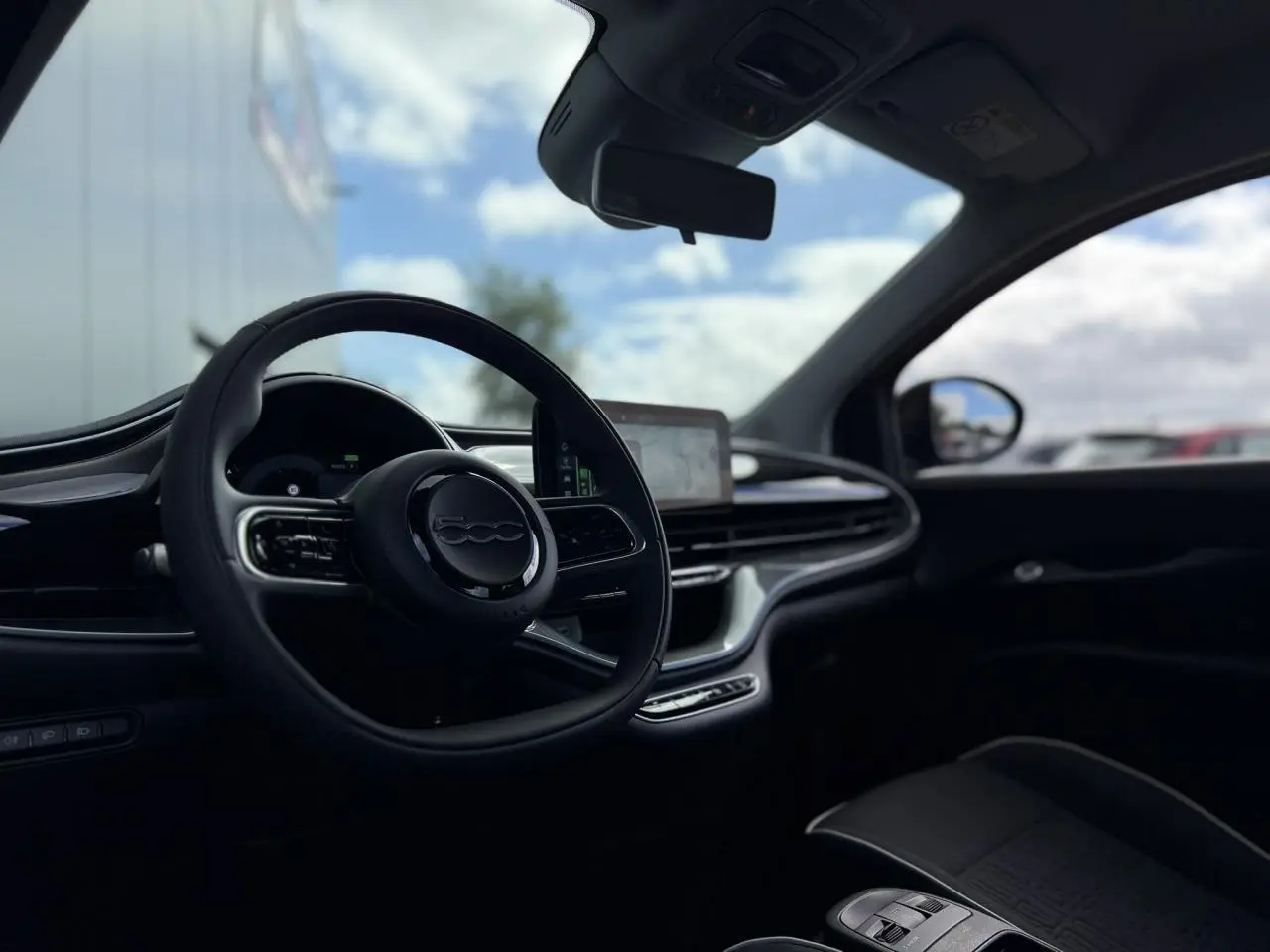 Intérieur de la Fiat 500 électrique 2024 vu côté conducteur, volant noir Soft-Touch et écran tactile central.