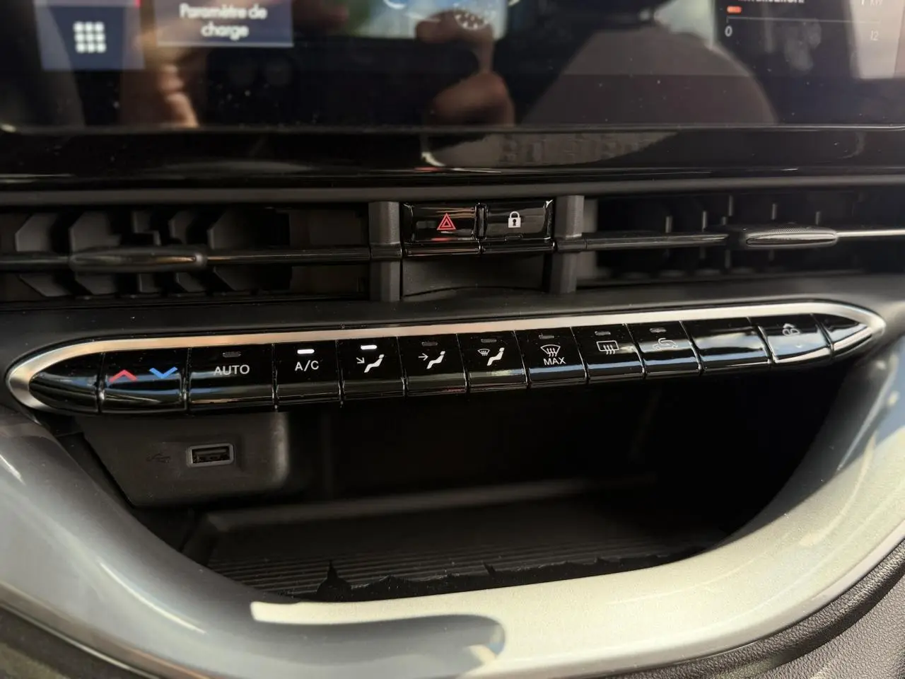 Gros plan sur la console centrale noire de la Fiat 500 électrique 2024, montrant les commandes de climatisation et un port USB.