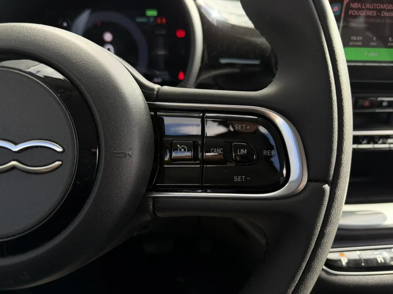 Gros plan sur le volant noir Soft-Touch du Fiat 500 électrique 2024, avec commandes intégrées au côté droit.