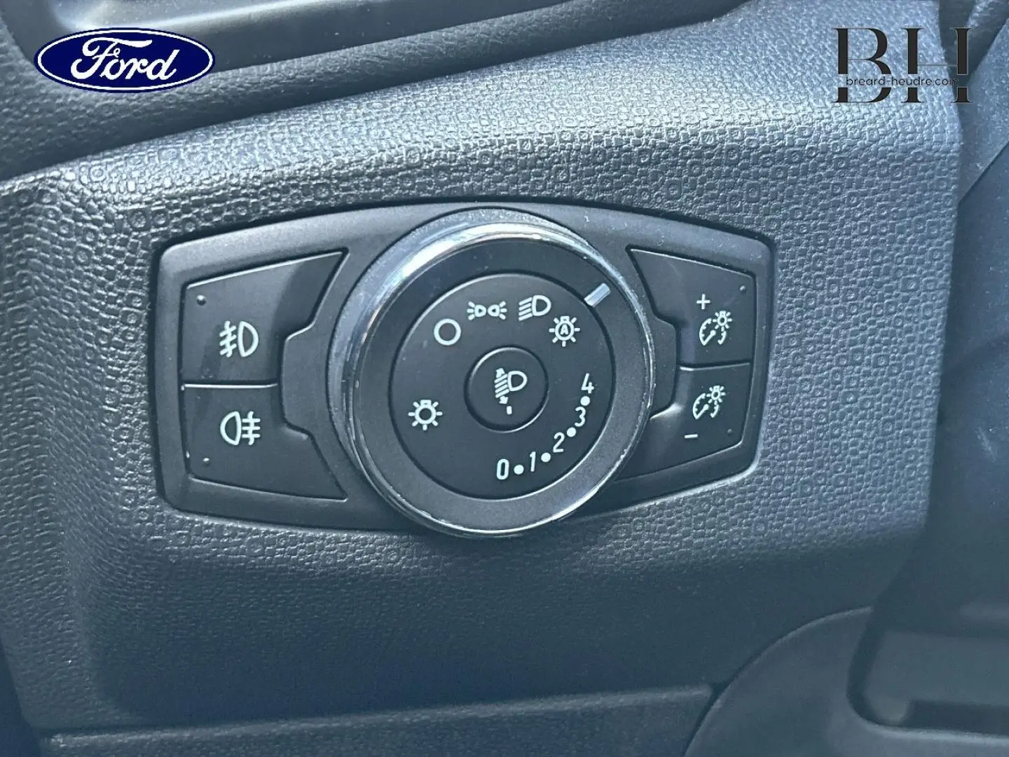 Gros plan sur le bouton de réglage des phares du Ford EcoSport 2018, intérieur noir texturé.