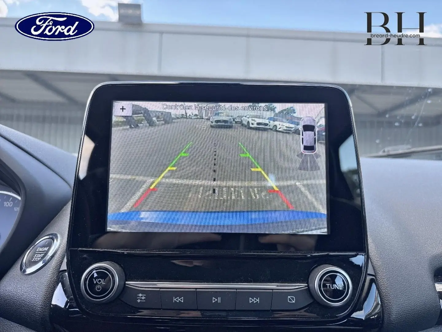 Écran tactile intérieur montrant la caméra de recul d'un Ford EcoSport bleu Lightning, avec commandes autour.