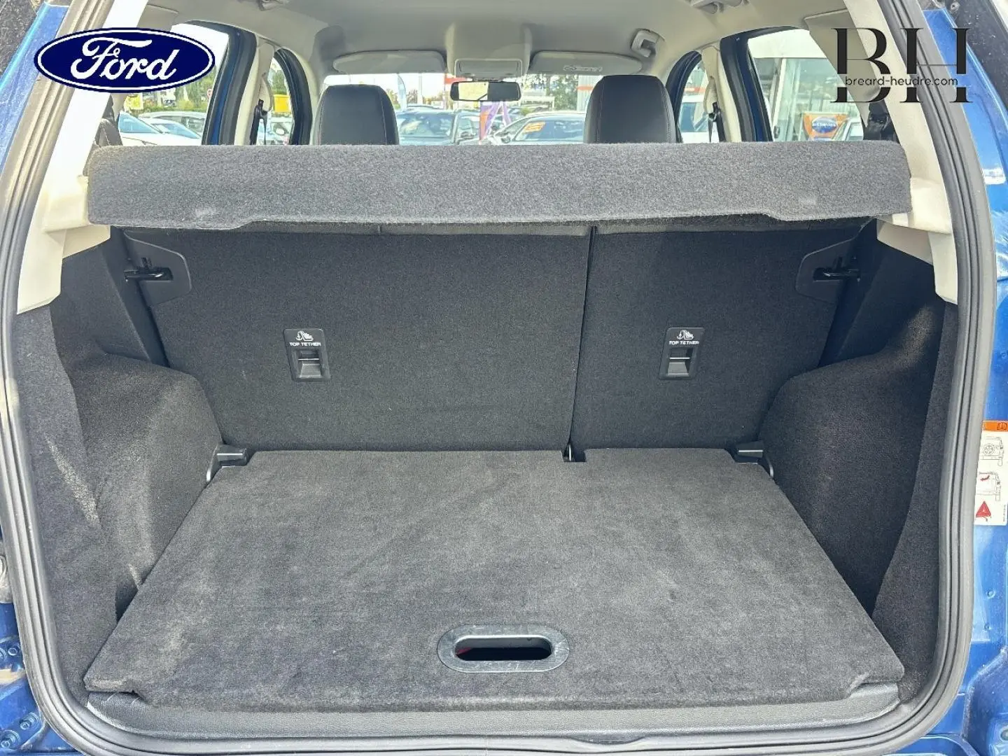 Vue arrière du coffre ouvert d’un Ford EcoSport bleu Lightning, montrant l’espace de chargement et la banquette arrière noire.