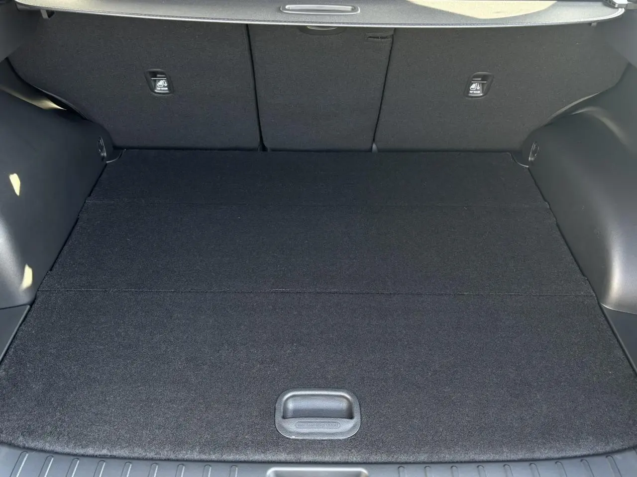 Coffre ouvert vu de l'intérieur d'un Hyundai Tucson Cypress Green 2025, espace de chargement plat et noir.