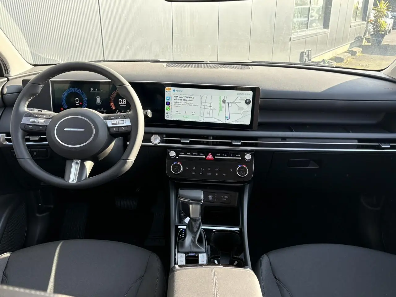 Vue intérieure avant du Hyundai Tucson 2025 avec tableau de bord numérique et écran tactile large, finition noire élégante.