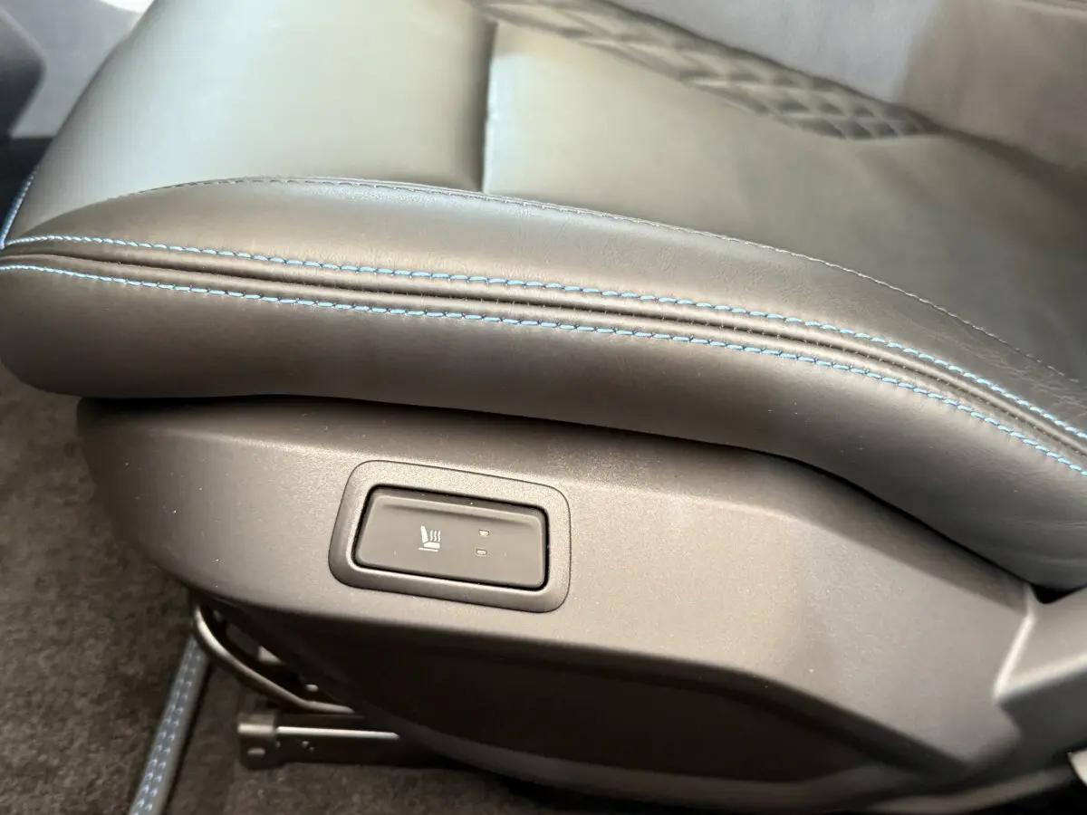 Gros plan sur le bouton de siège chauffant intégré à la garniture cuir noire avec surpiqûres bleues de l'Alpine A110 Legende 2019.