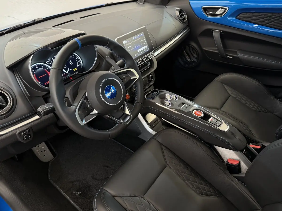 Vue intérieure côté conducteur de l'Alpine A110 Légende 2019, volant cuir avec bande bleue et inserts bleus sur porte.