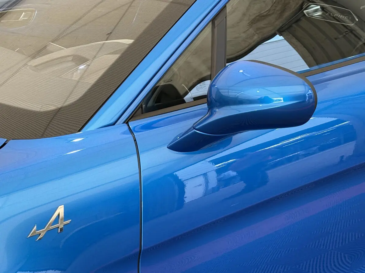 Détail du côté gauche bleu brillant de l'Alpine A110 Legende 2019 avec rétroviseur et logo "A" visible.