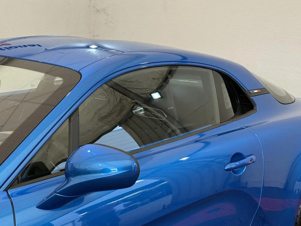 Vue côté gauche rapprochée de l'ALPINE A110 Legende bleu brillant avec rétroviseur et poignée de porte visibles.