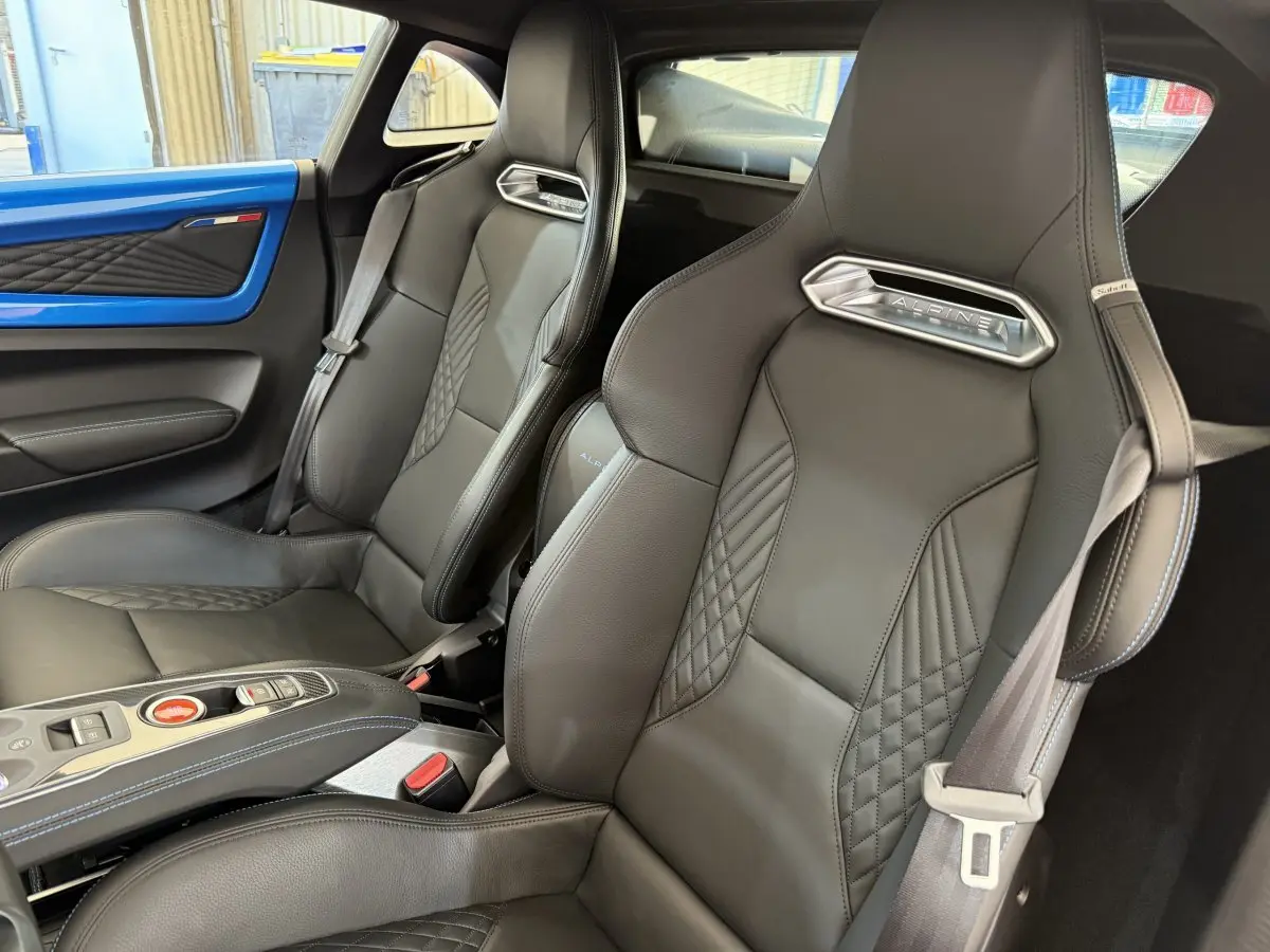 Gros plan sur les sièges en cuir noir matelassé de l'Alpine A110 Légende avec insert bleu visible côté porte.