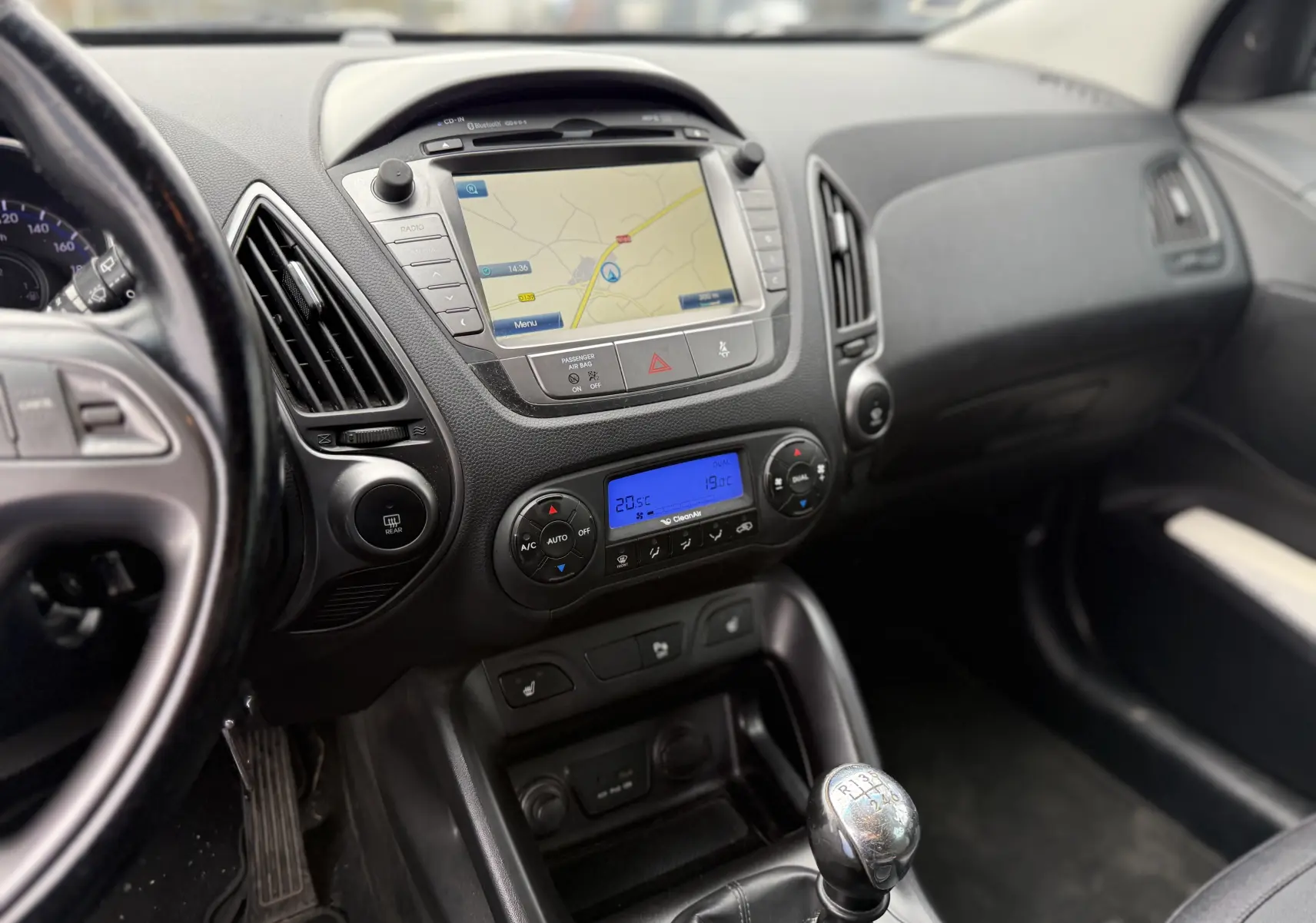Vue intérieure du tableau de bord du Hyundai ix35 blanc de 2014, avec navigation GPS et levier de vitesses manuel visible.